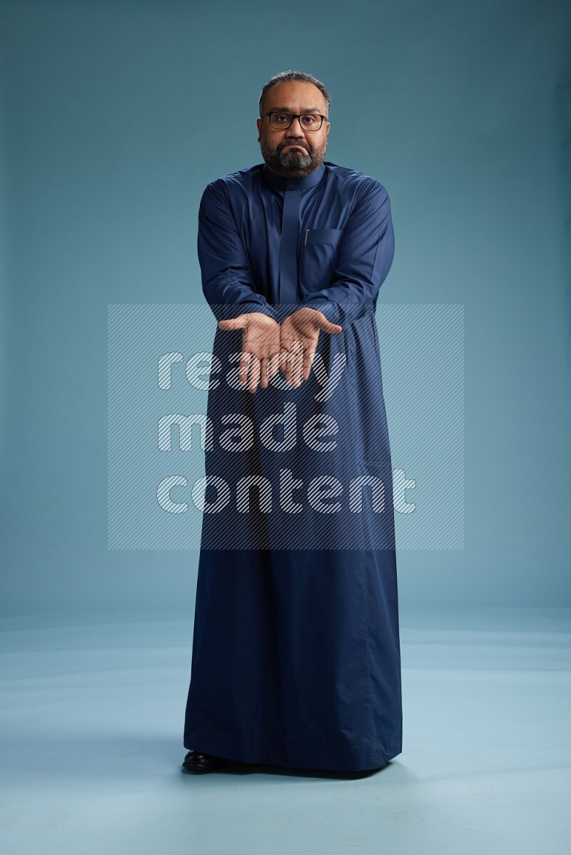 Saudi Man without shimag Standing Interacting with the camera on blue background