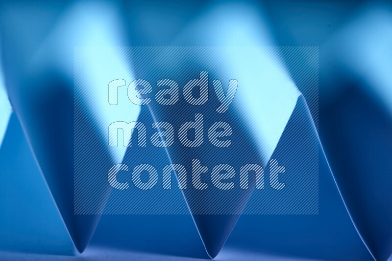 A close-up abstract image showing sharp geometric paper folds in blue gradients