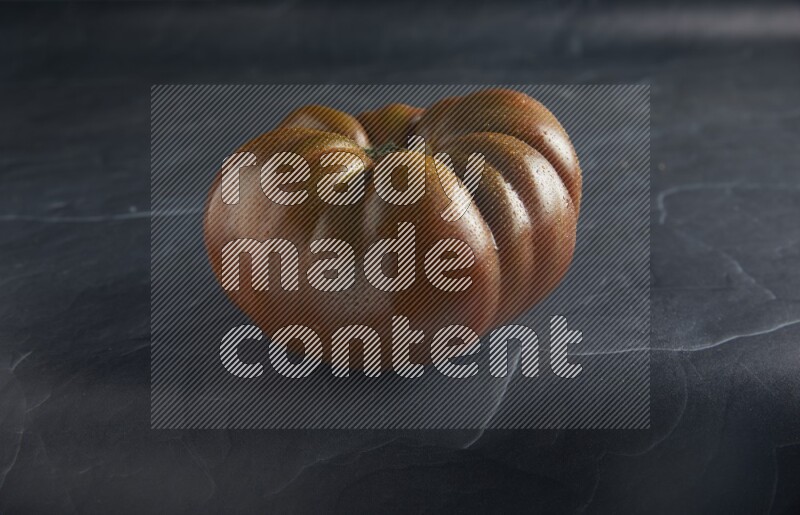 45 degree single heirloom tomato on a textured black slate background
