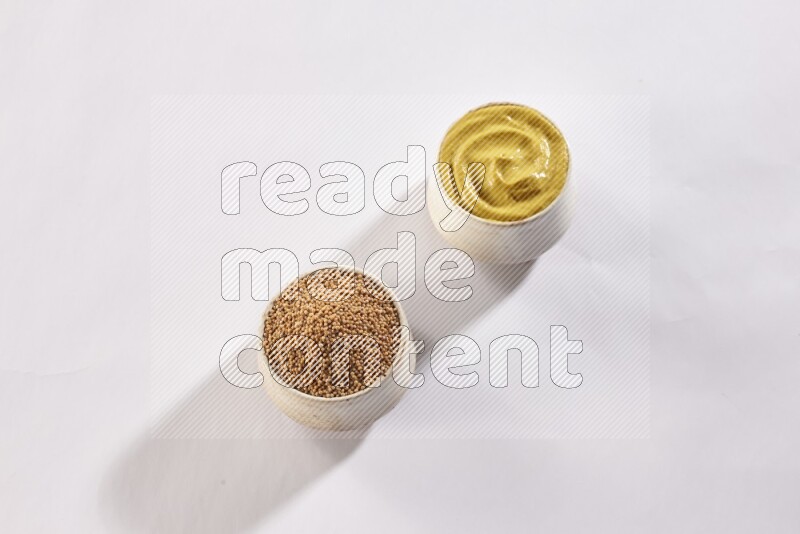2 beige pottery bowls full of mustard seeds and mustard paste on white flooring in different angles
