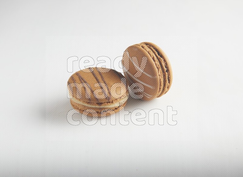 45º Shot of of two assorted Brown Irish Cream, and light brown  Almond Cream macarons on white background