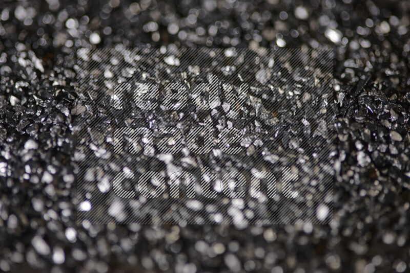 Black shimmering fragments of glass scattered on a black background