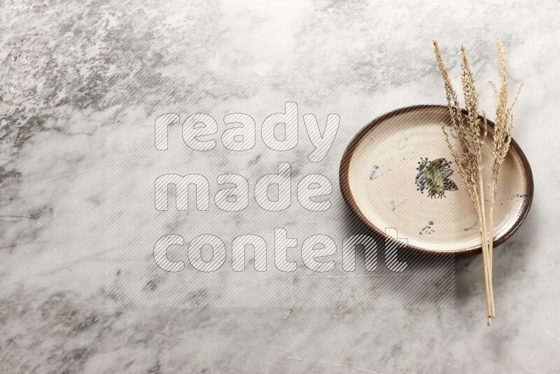 Wheat stalks on decorative pottery plate on grey marble background