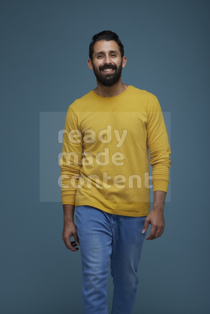 Man posing in a blue background wearing a yellow shirt