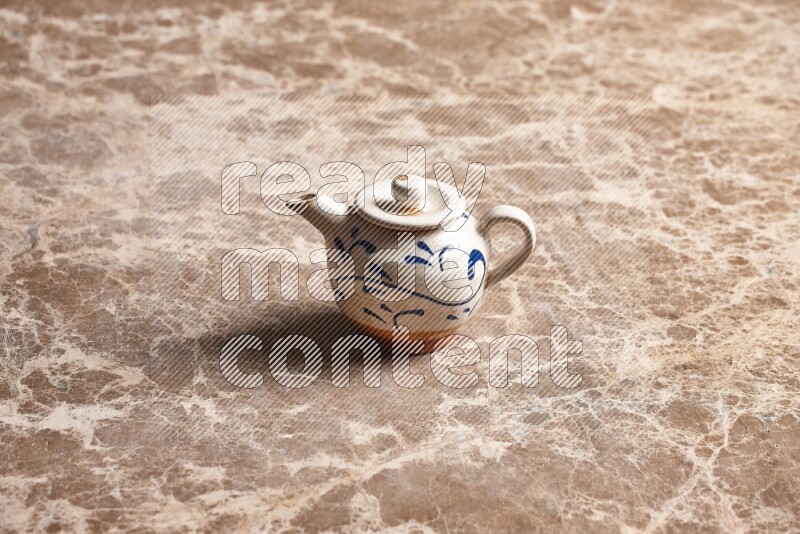 A pottery teapot on beige marble background