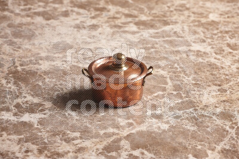 A small copper pot on beige marble background