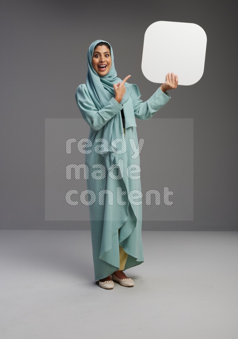 Saudi Woman wearing Abaya standing holding social media sign on Gray background