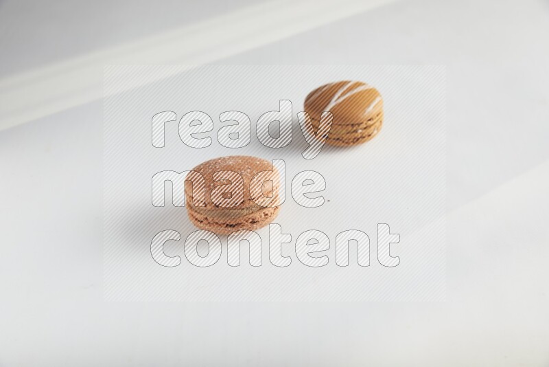45º Shot of of two assorted Brown Irish Cream, and Brown Hazelnuts macarons on white background