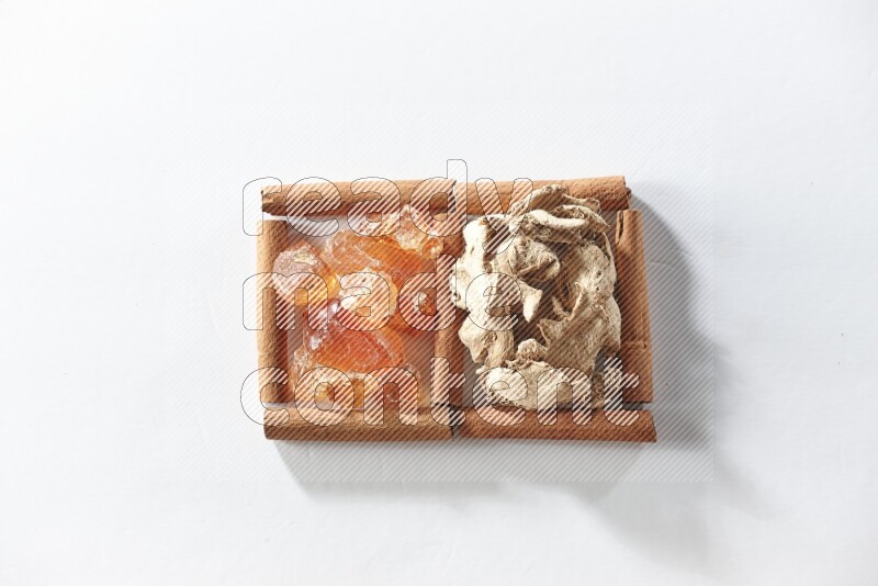 مربعان من أعواد القرفة ممتلئان بالزنجبيل المجفف والصمغ العربي علي خلفية بيضاء