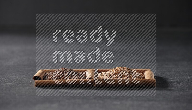 2 squares of cinnamon sticks full of mustard seeds and flaxseeds on black flooring