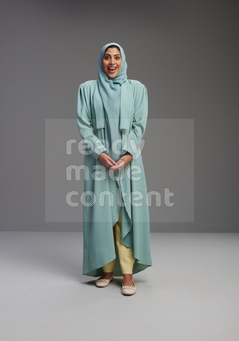 Saudi Woman wearing Abaya standing interacting with the camera on Gray background