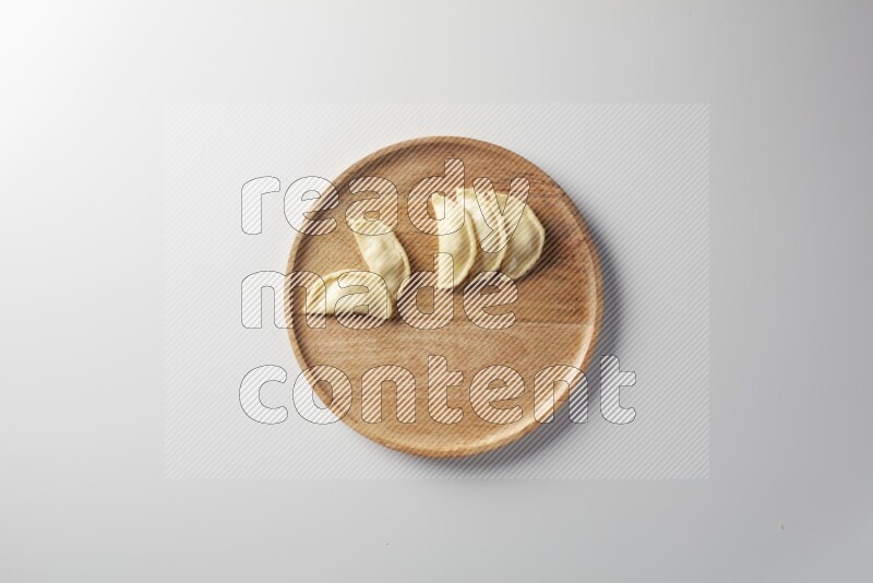 Five Sambosas on a wooden round plate on a white background