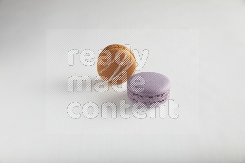 45º Shot of of two assorted Brown Irish Cream, and Purple Blueberry macarons on white background