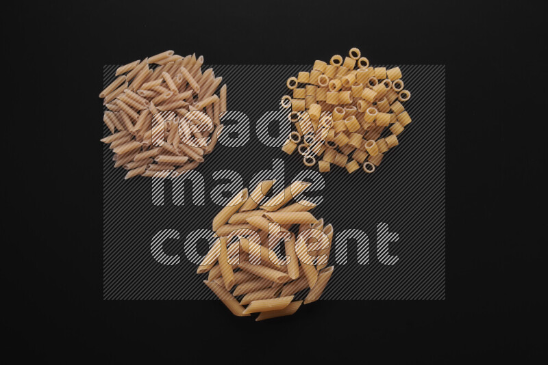 Different pasta types in bunches on black background