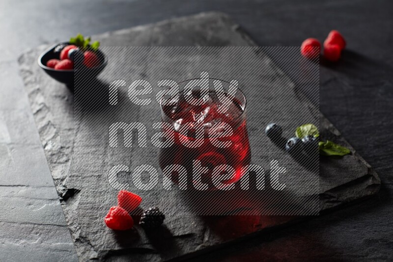 A glass of mixed berries juice on black background