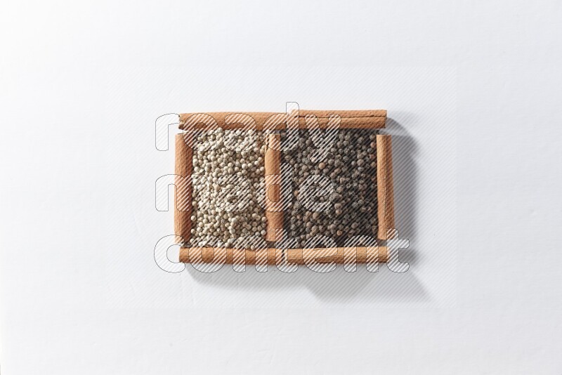 2 squares of cinnamon sticks full of black pepper and white pepper on white flooring