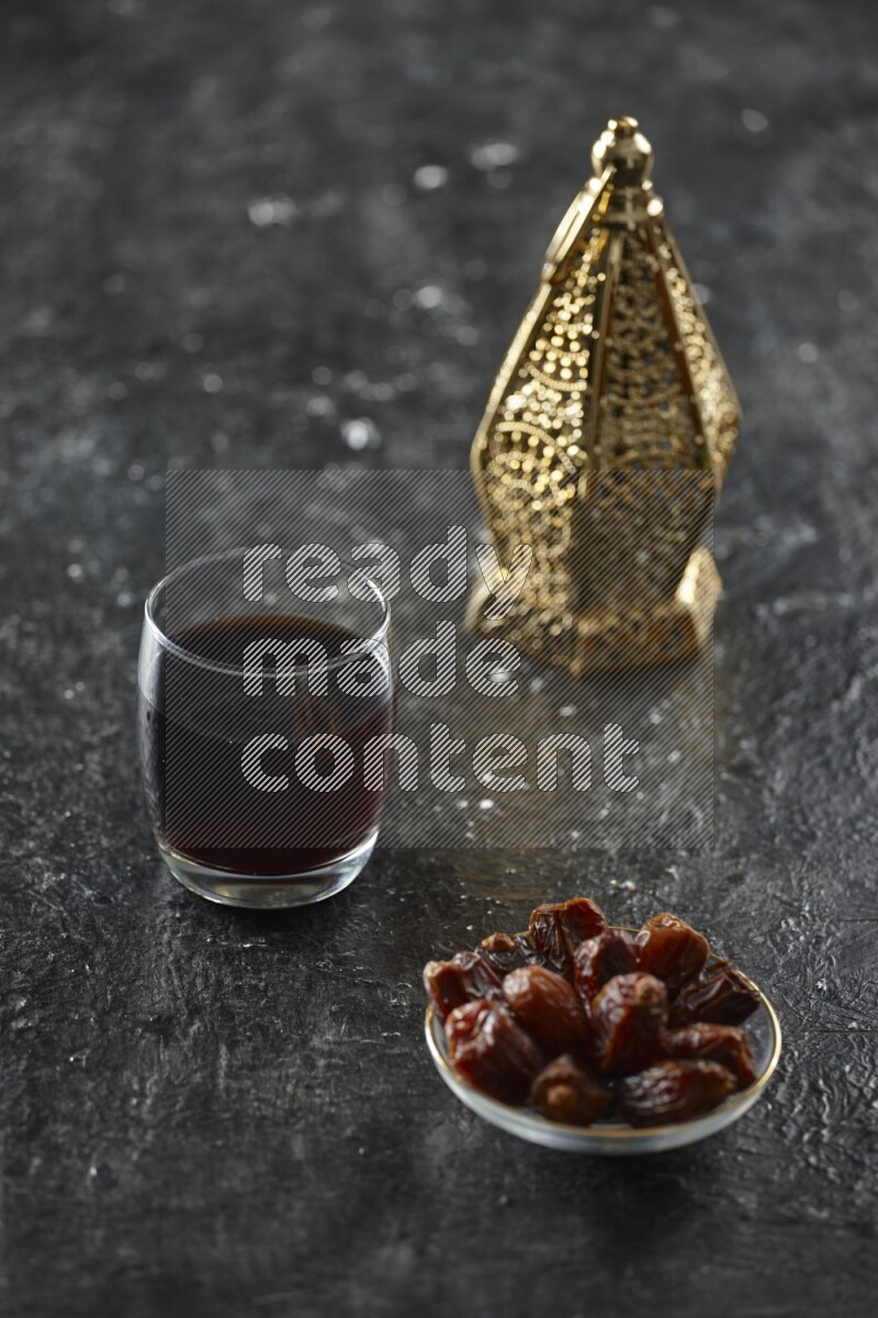 A golden lantern with different drinks, dates, nuts, prayer beads and quran on textured black background