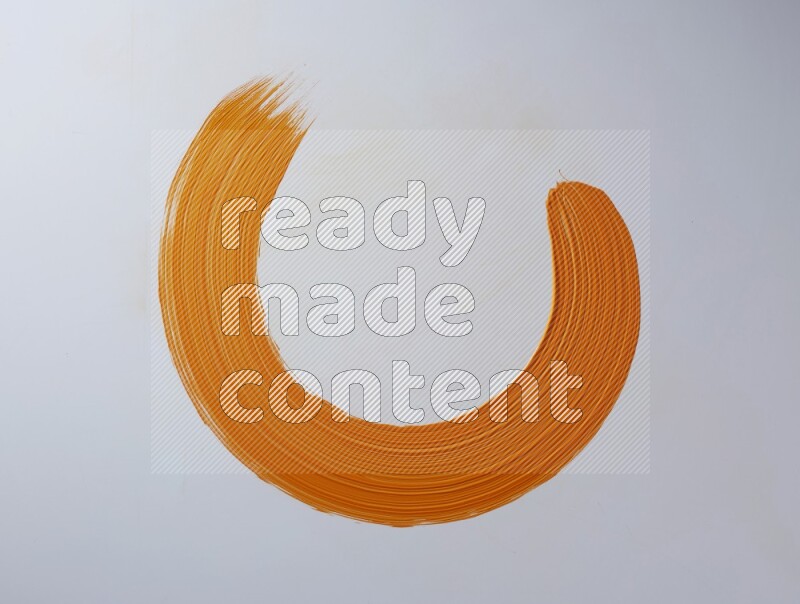 An orange circular painting brush stroke on white background