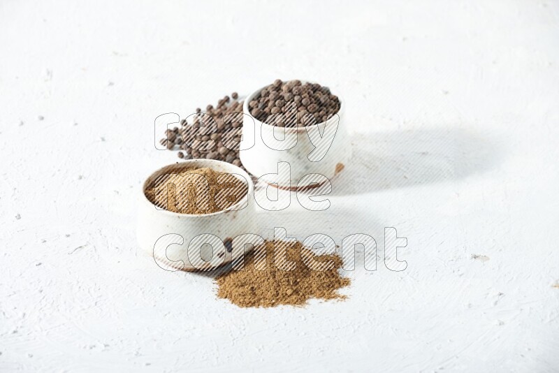 وعاءان بيج، أحدهما ممتلئ ببودرة بهار الفلفل الحلو والآخر بالحبوب مع البودرة والحبوب متناثرة على خلفية بيضاء