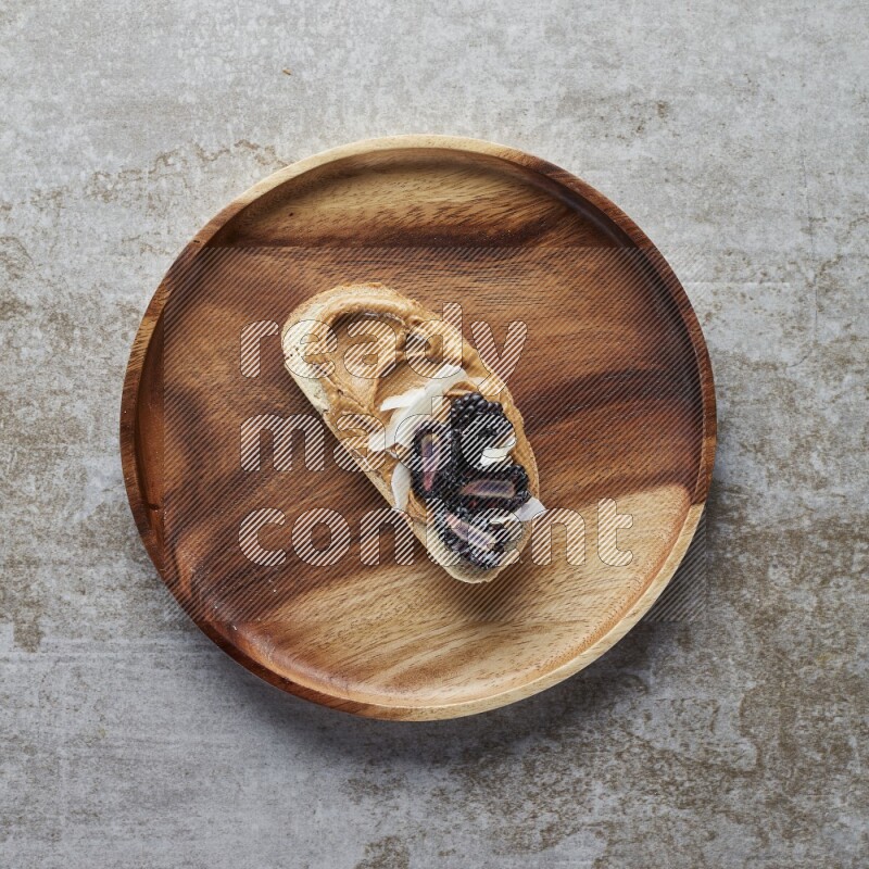 open faced peanut butter sandwich with blackberries  and coconut flakes on a  grey textured background