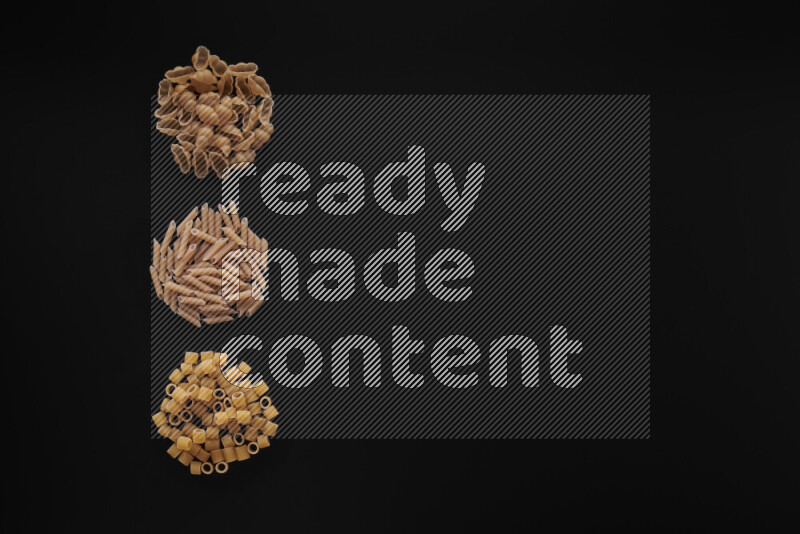 Different pasta types in 3 bunches on black background