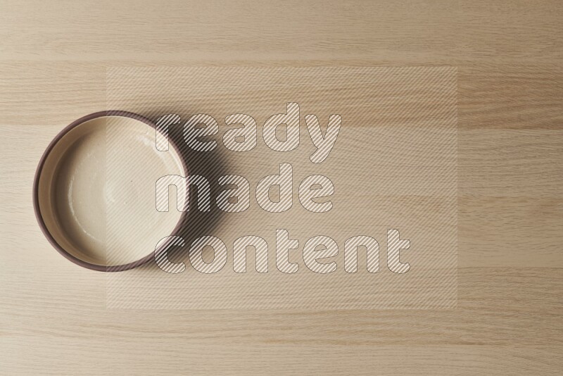 A beige pottery oven bowl on light wooden background