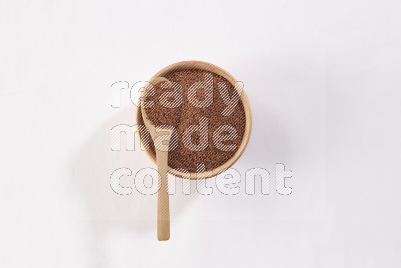 A wooden bowl and spoon full of garden cress seeds on a white flooring