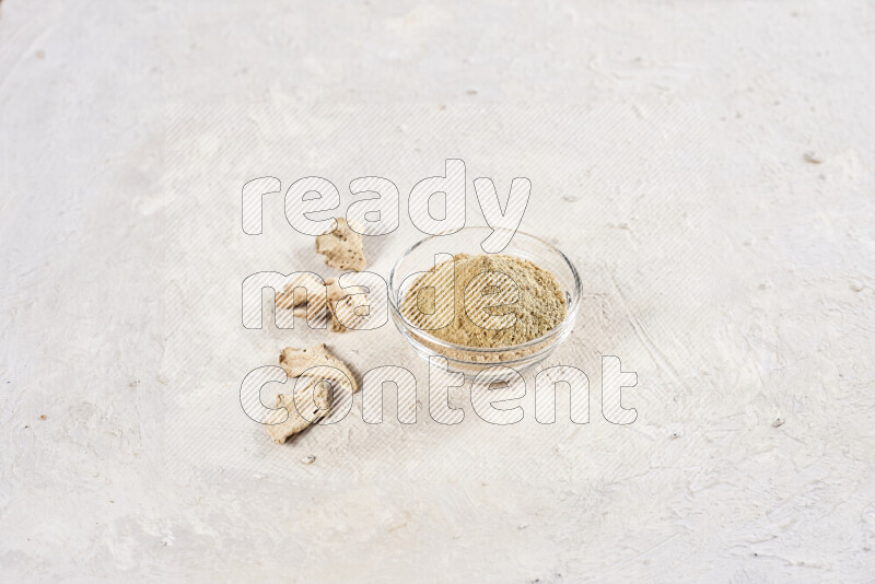 A glass bowl full of ground ginger powder on white background