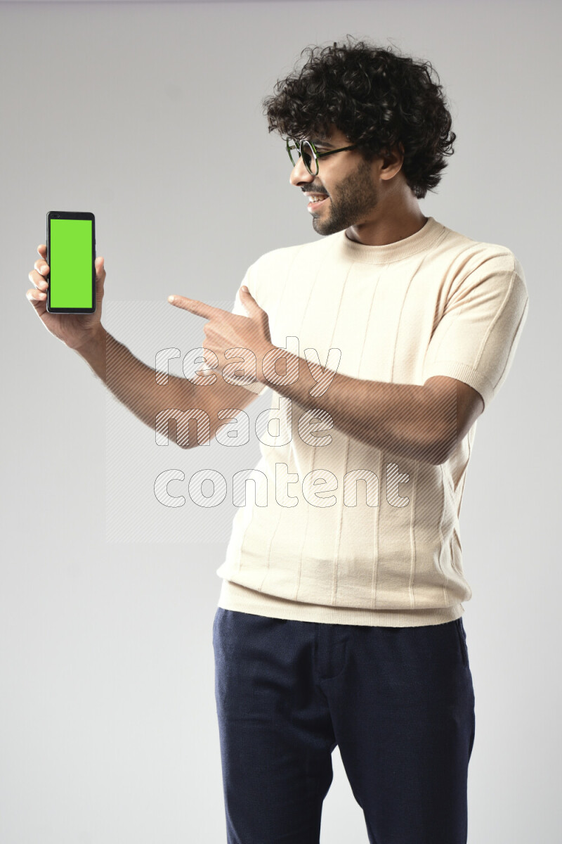 A man wearing casual standing and showing a phone screen on white background