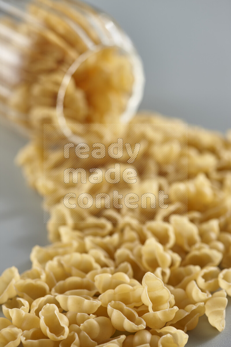 Flipped jar full of raw pasta on light blue background