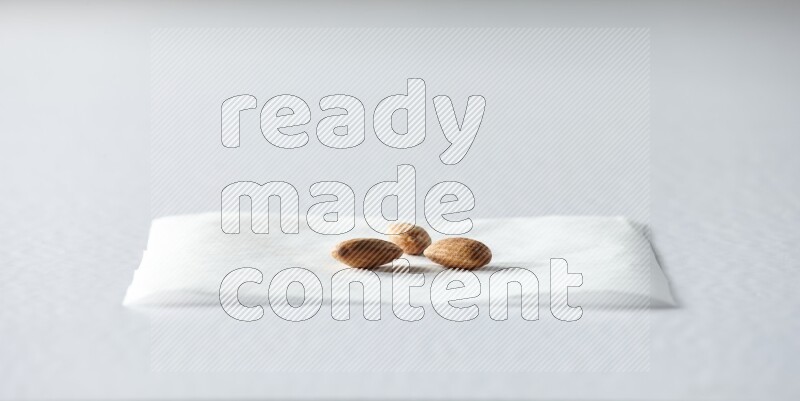 3 peeled almonds on a piece of paper on a white background in different angles