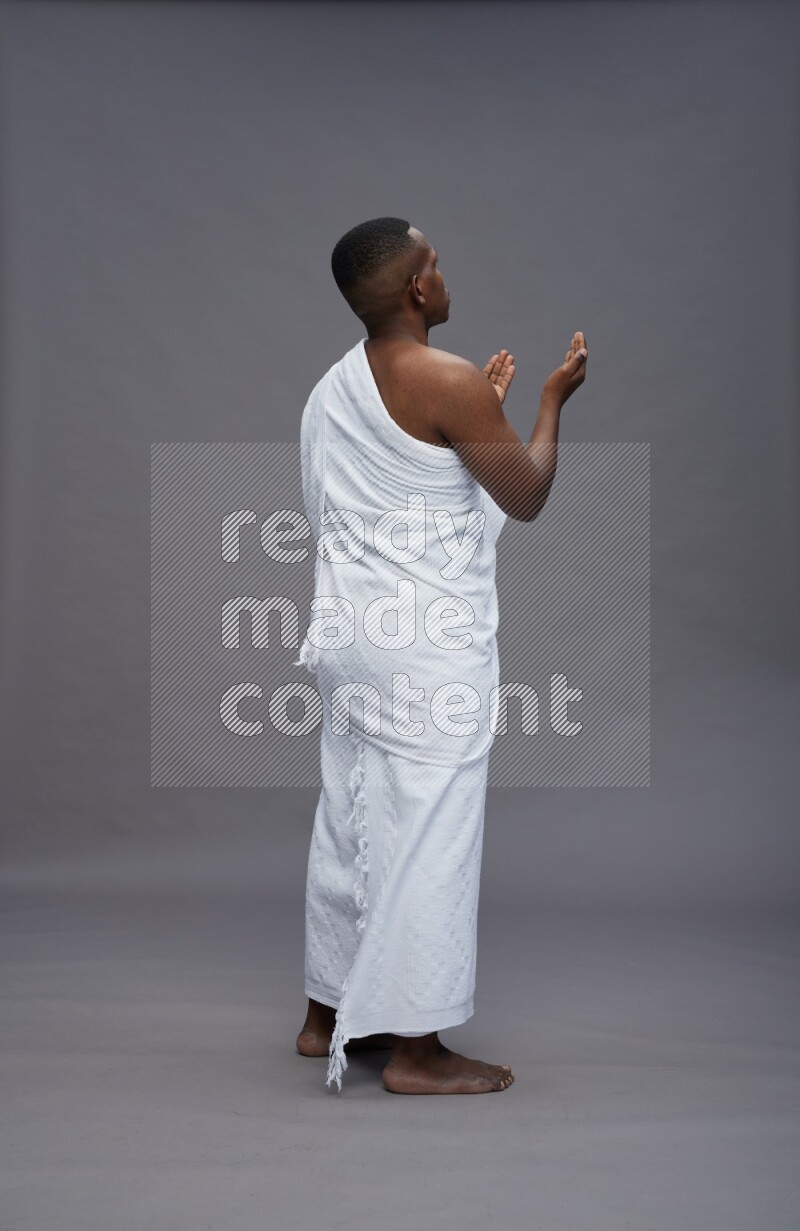 A man wearing Ehram Standing dua'a on gray background