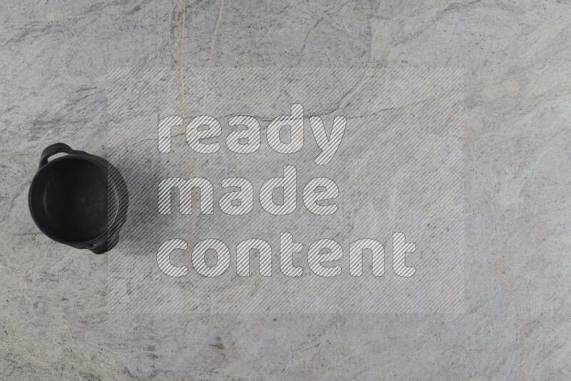A black pottery bowl on grey marble background