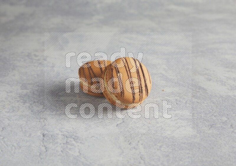 45º Shot of two light brown  Almond Cream macarons  on white  marble background
