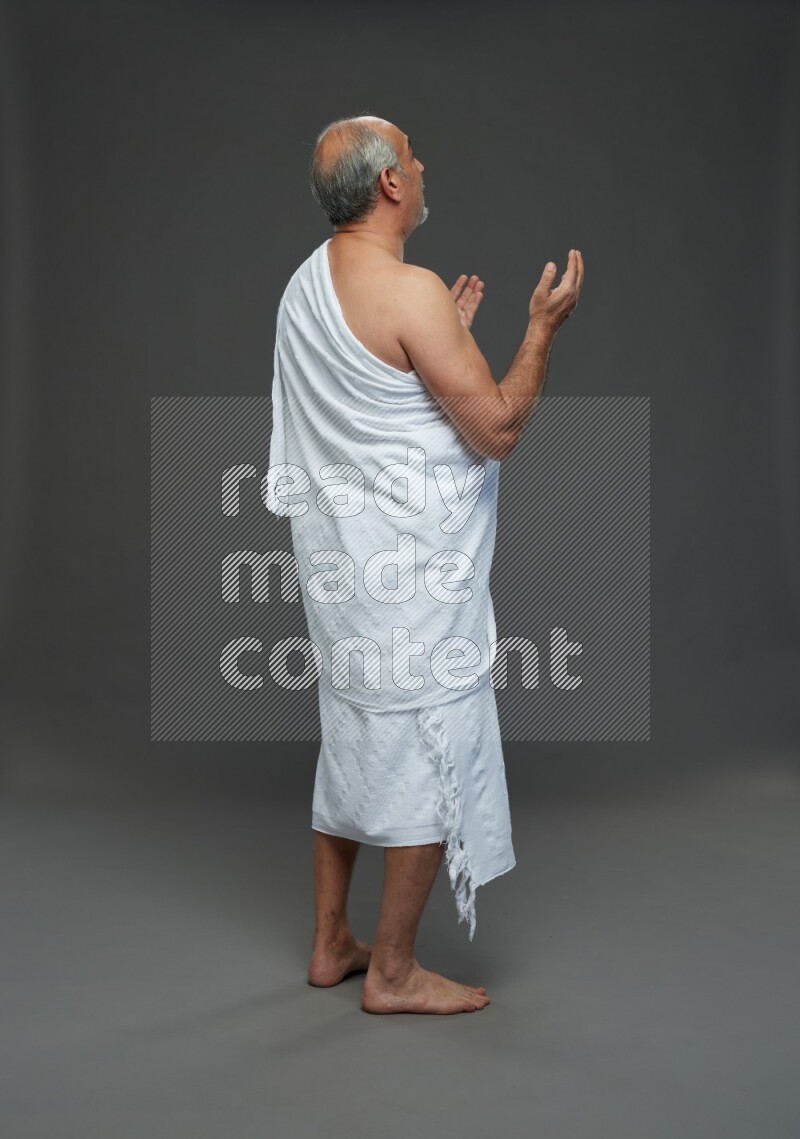 A man wearing Ehram Standing dua'a on gray background