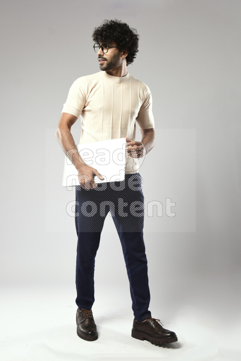A man wearing casual standing and holding a laptop on white background