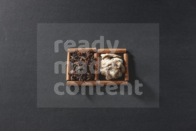 2 squares of cinnamon sticks full of star anise and dried ginger on black flooring