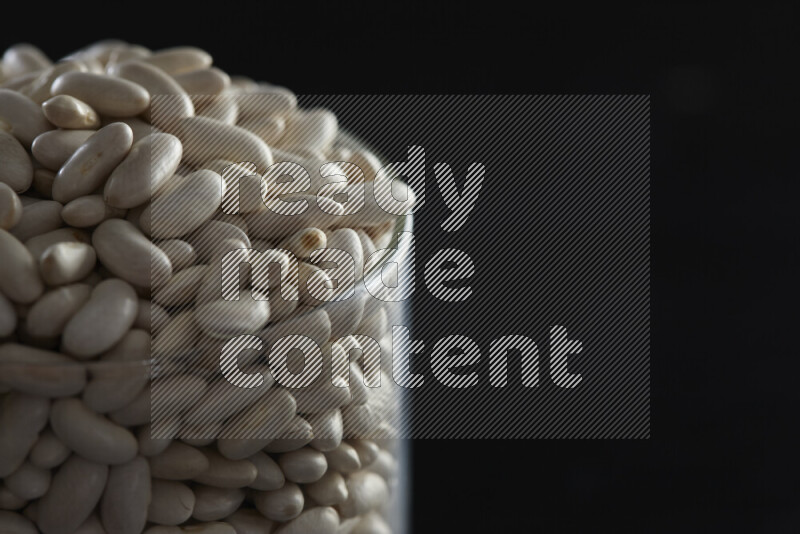 White beans in a glass jar on black background