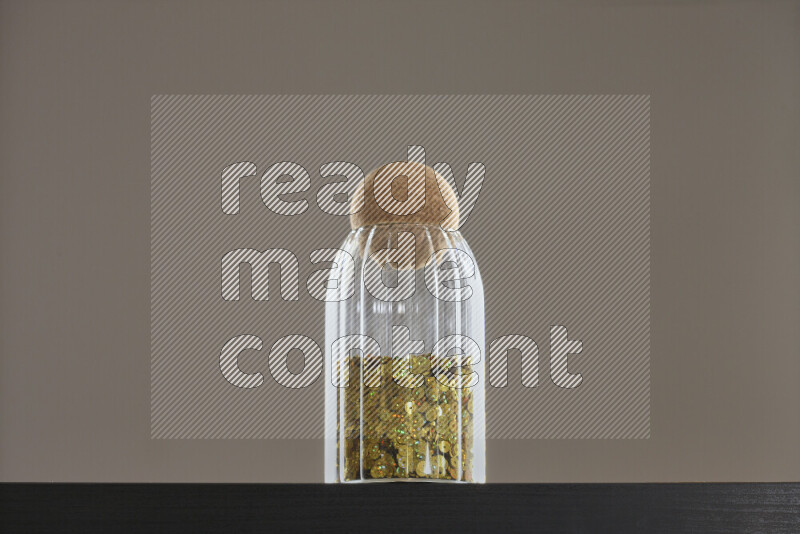 Sequins in a glass jar on black background