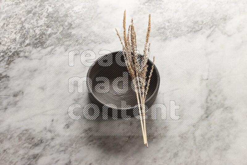 Wheat stalks on Black Pottery Oven Plate on grey marble flooring, 45 degree angel