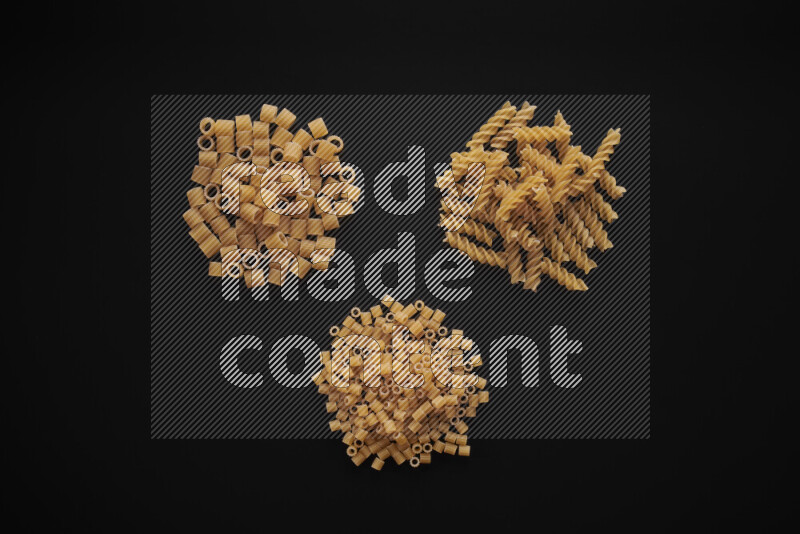 Different pasta types in bunches on black background