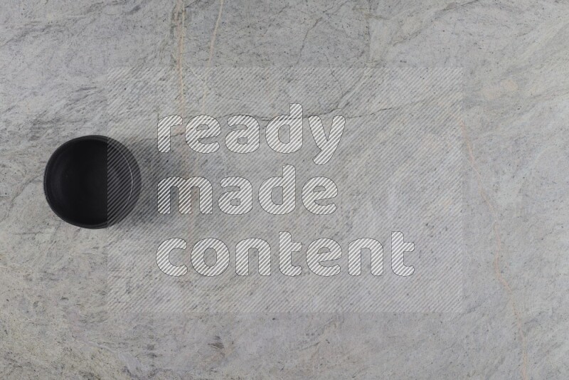 A black pottery bowl on grey marble background