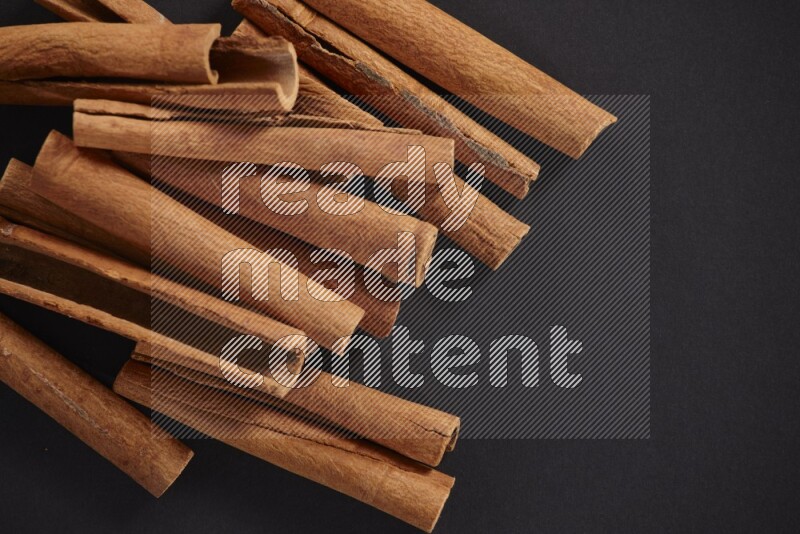 Cinnamon sticks stacked on black flooring