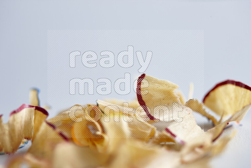 A close-up showing a small pile of pencil shavings with varied color edges on grey background