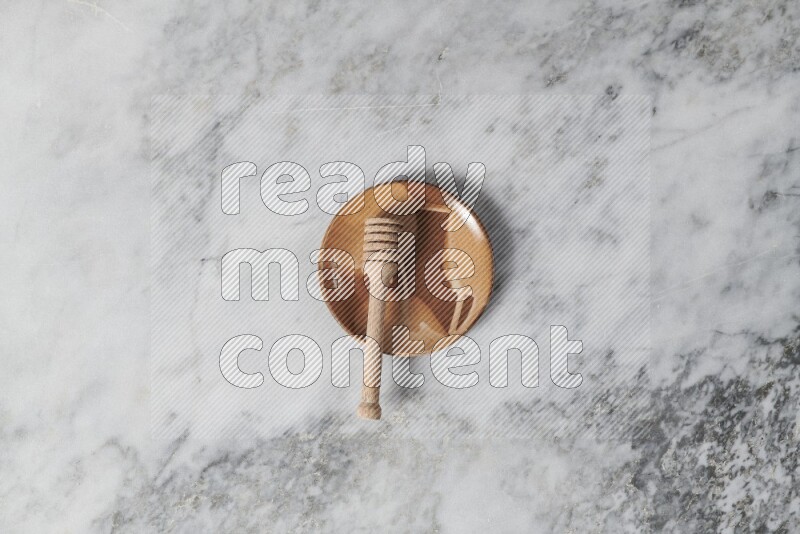 Multicolored pottery plate with wooden honey dipper in it on grey marble background