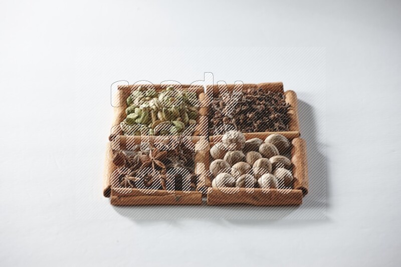 4 squares of cinnamon sticks full of cardamom, star anise, cloves and nutmeg on white flooring