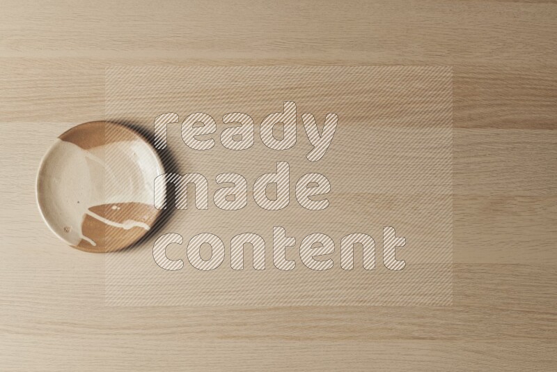 A multicolored pottery plate on light wooden background