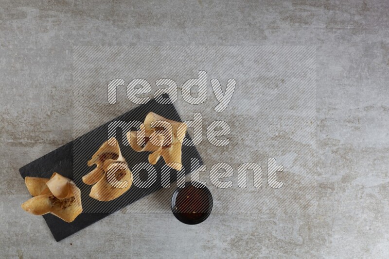 wonton cups with soy sauce ramkin on rectangle slate on grey textured counter top