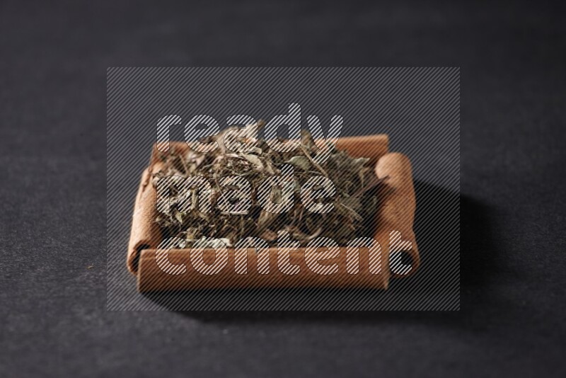A single square of cinnamon sticks full of dried basil on black flooring