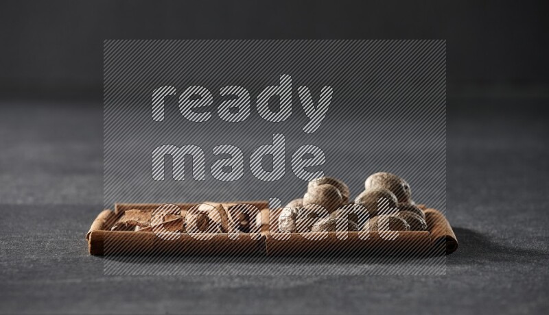 2 squares of cinnamon sticks full of cinnamon and nutmeg on black flooring